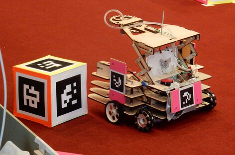Robot with a scissor lift mechanism next to a token covered in fiducial markers